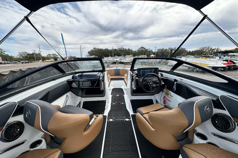 Slide: The Image of 2023 Scarab 215 ID boat interior with modern seating and dashboard, under a cloudy sky. - 19