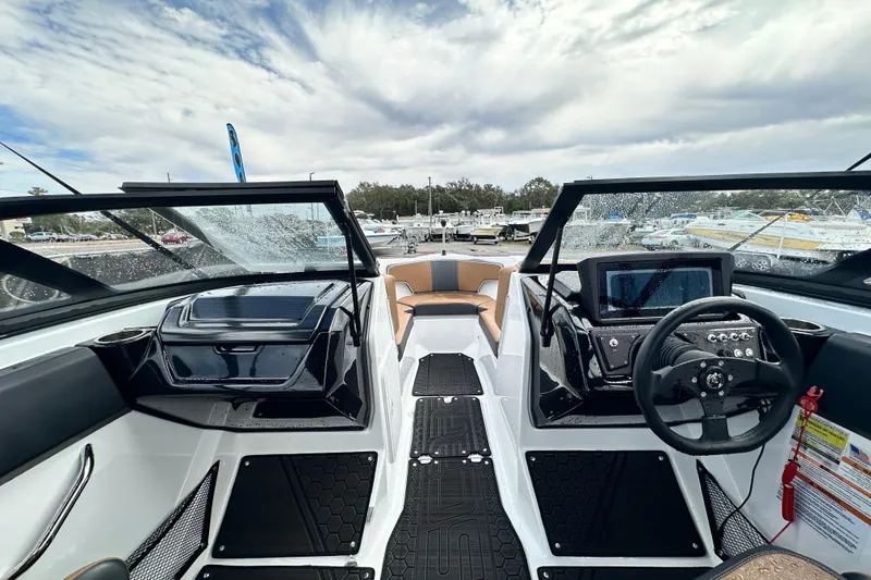 Slide: The Image of 2023 Scarab 215 ID boat interior with modern dashboard and seating under cloudy sky. - 22