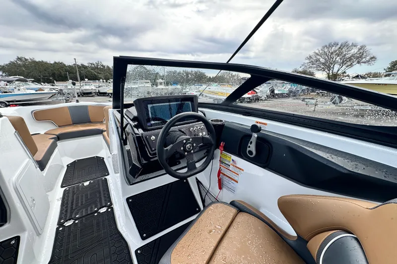 Slide: The Image of 2023 Scarab 215 ID boat interior with modern dashboard and seating, wet from rain. - 23