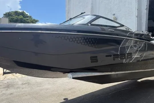 Slide: The Image of 2023 Scarab 215 ID boat on trailer under cloudy sky at dealership. - 3
