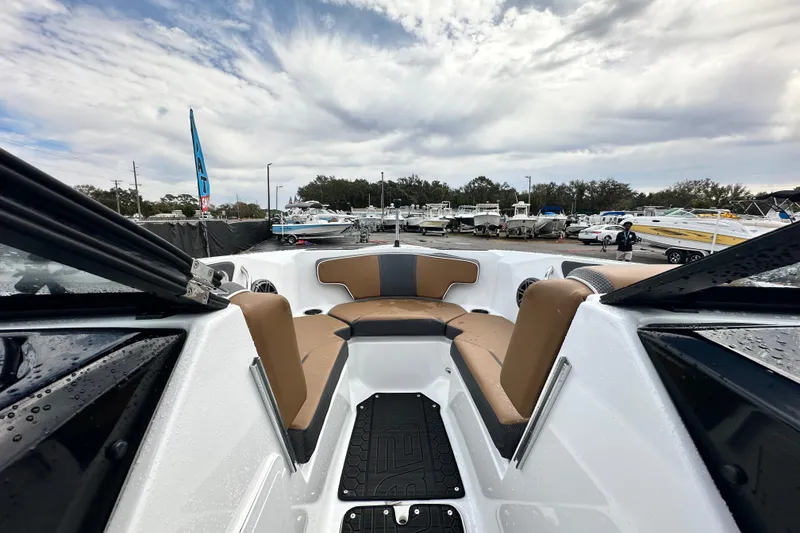 Slide: The Image of 2023 Scarab 215 ID boat interior with tan seating, displayed at a marina under cloudy skies. - 34