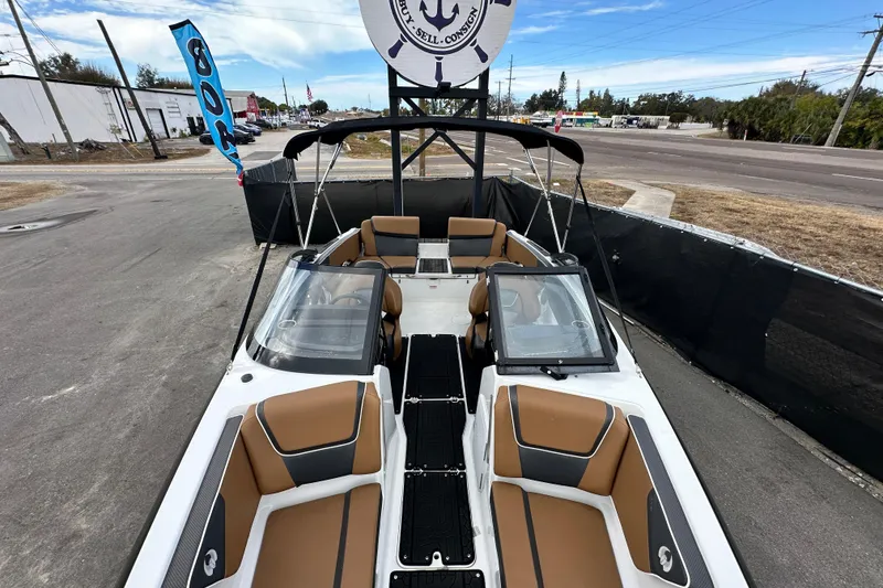 Slide: The Image of 2023 Scarab 215 ID boat with tan seating, displayed outdoors near a road. - 46