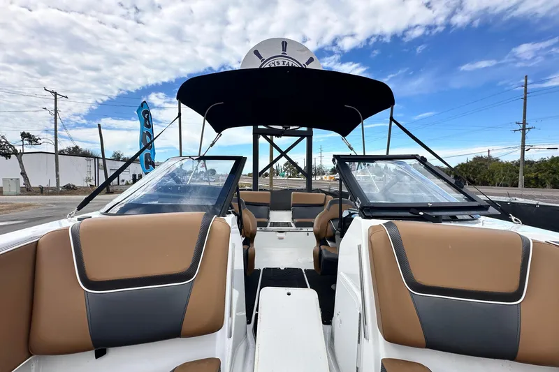 Slide: The Image of 2023 Scarab 215 ID boat interior with tan and black seating under a blue sky. - 49