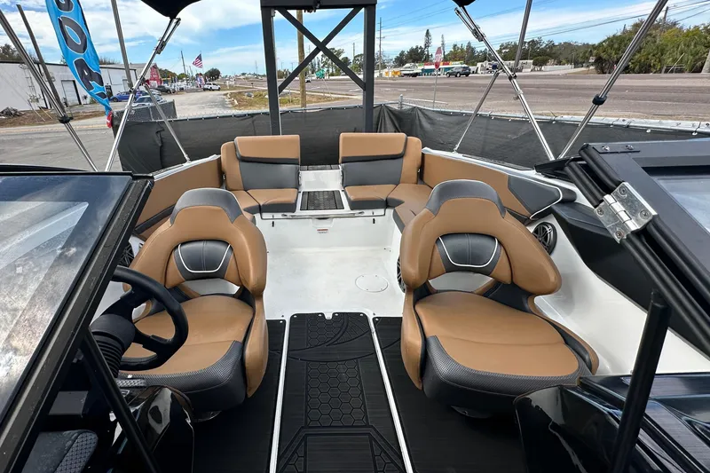 Slide: The Image of 2023 Scarab 215 ID boat interior with tan and black seating, steering wheel, and canopy. - 52