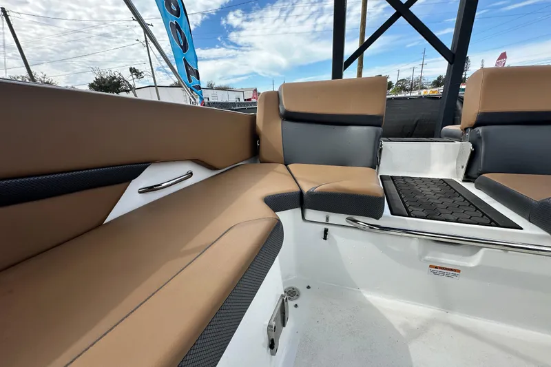 Slide: The Image of 2023 Scarab 215 ID boat interior with tan and black seating, under a partly cloudy sky. - 58
