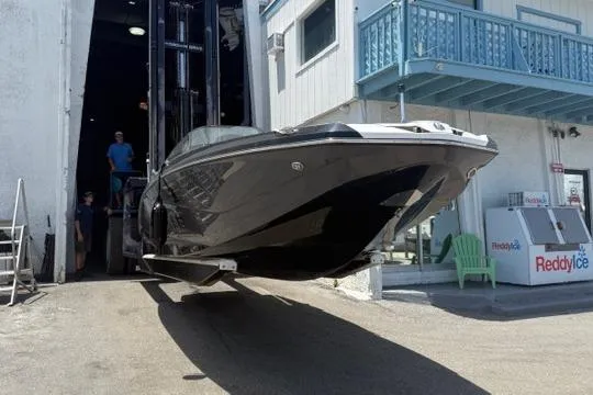 Slide: The Image of 2023 Scarab 215 ID boat on trailer, parked outdoors under cloudy sky. - 6