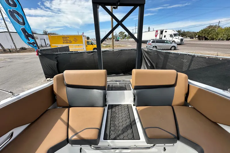 Slide: The Image of 2023 Scarab 215 ID boat interior with tan and gray seating, parked outdoors. - 62