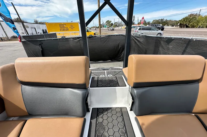 Slide: The Image of 2023 Scarab 215 ID boat interior with tan and gray seating, outdoor setting. - 63