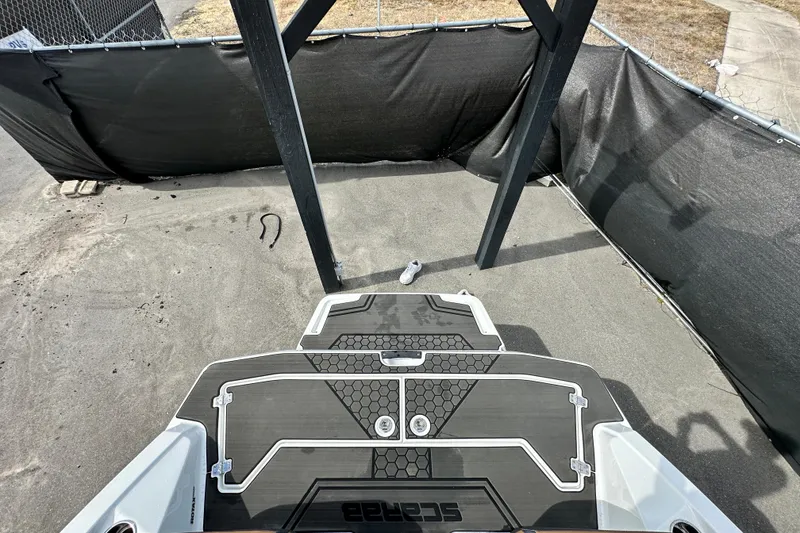 Slide: The Image of 2023 Scarab 215 ID boat deck with black and white design, parked on concrete. - 66