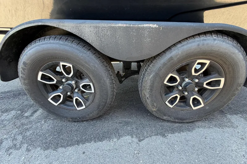 Slide: The Image of 2023 Scarab 215 ID trailer wheels on asphalt surface, showcasing dual black tires. - 75