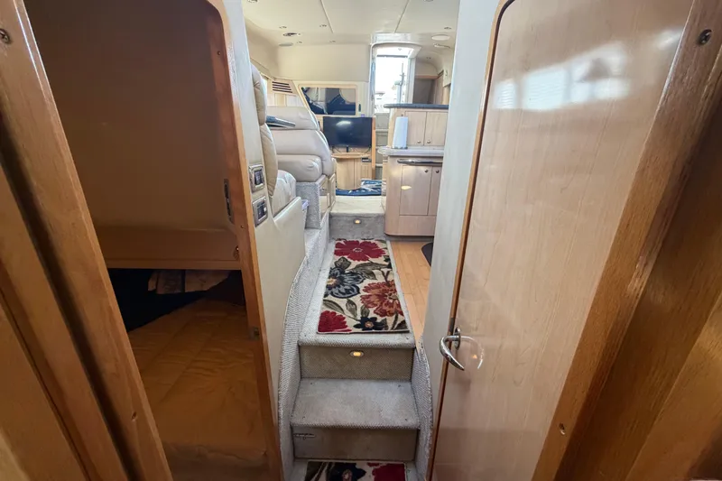 Slide: The Image of 2002 Sea Ray 480 Motor Yacht interior with carpeted stairs and cozy living area. - 22