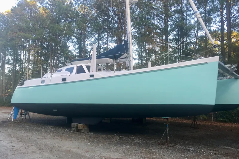 The Image of 2003 Chris White Atlantic 42 catamaran on land, surrounded by trees. - 0
