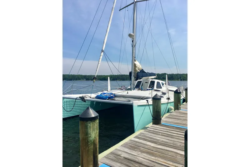 Slide: The Image of 2003 Chris White Atlantic 42 catamaran docked at a marina, clear sky background. - 2