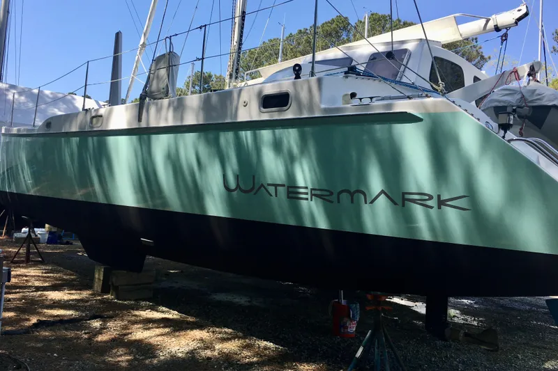 Slide: The Image of 2003 Chris White Atlantic 42 catamaran named "Watermark" on land, green hull, trees in background. - 4