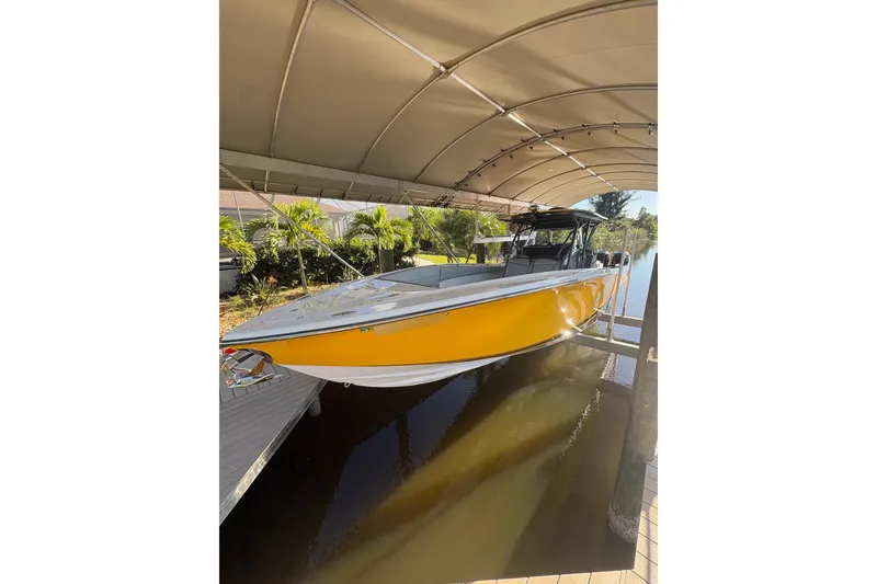 Slide: The Image of 2017 Nor-Tech 390 Sport Center Console boat in yellow, docked under a canopy. - 1