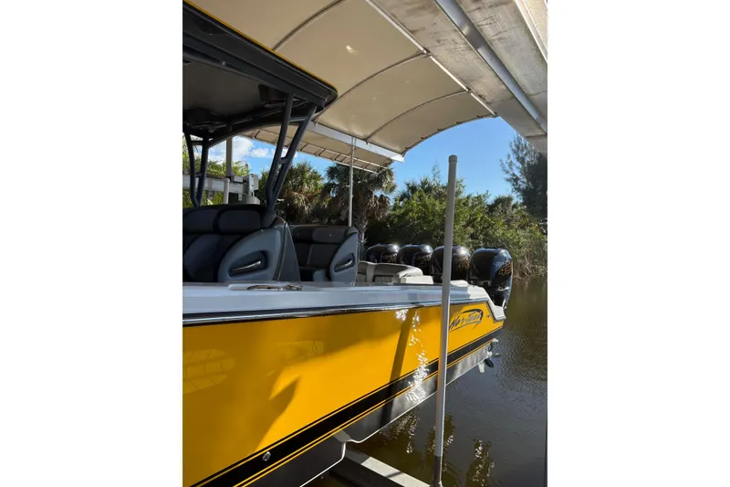 Slide: The Image of 2017 Nor-Tech 390 Sport Center Console boat with yellow hull, docked under canopy. - 3