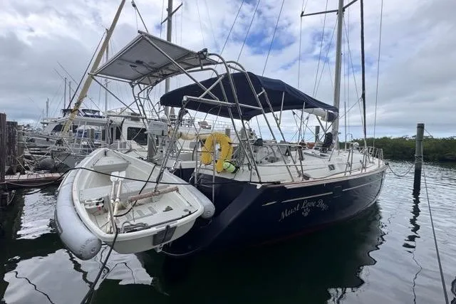 The Image of 1996 Beneteau 50 sailboat docked, featuring a dinghy and canopy, under cloudy skies. - 0