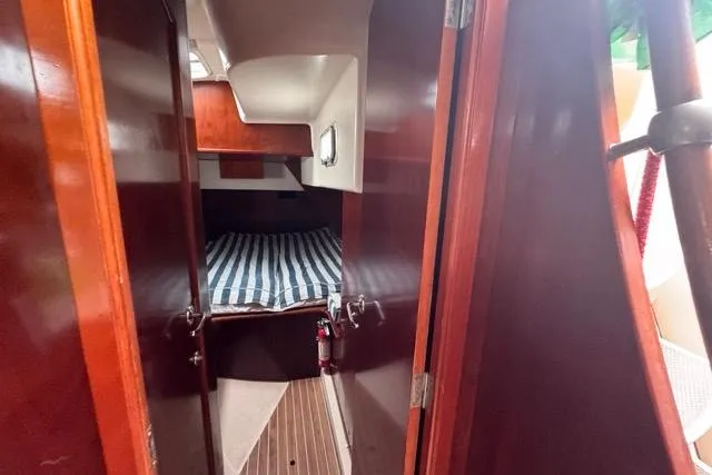 Slide: The Image of Interior cabin of 1996 Beneteau 50 sailboat with striped bedding and wooden finishes. - 101