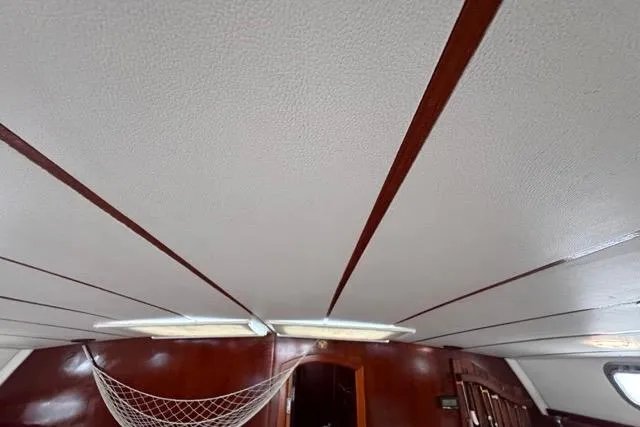 Slide: The Image of Interior view of 1996 Beneteau 50 yacht with wooden paneling and ceiling netting. - 105