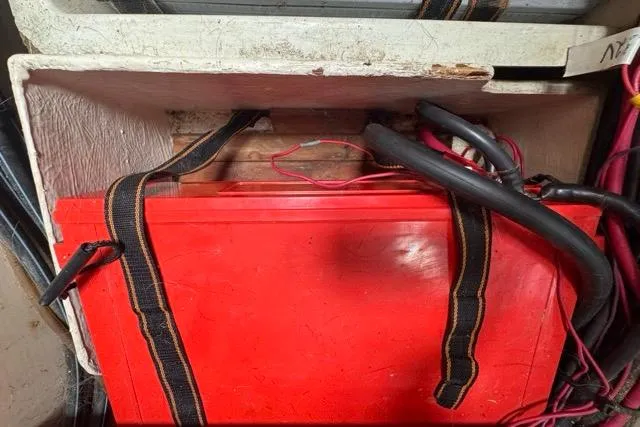 Slide: The Image of Red battery secured with straps in a 1996 Beneteau 50 sailboat compartment. - 113