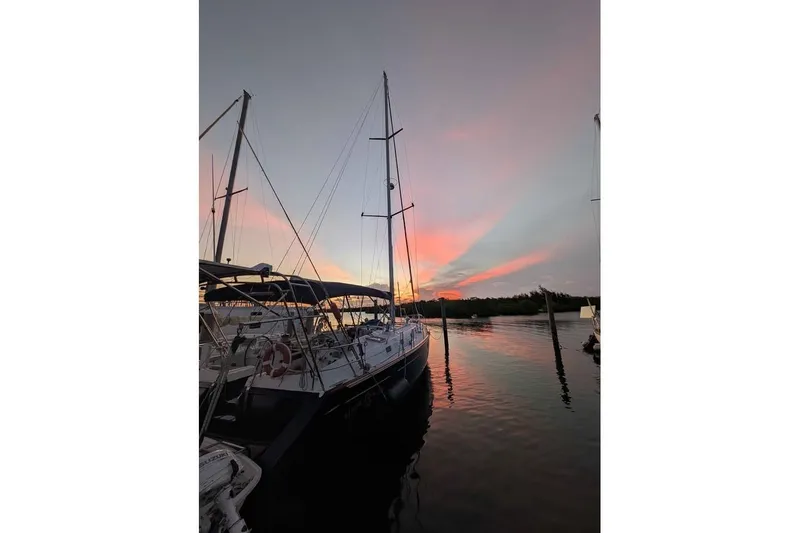 Slide: The Image of 1996 Beneteau 50 sailboat docked, featuring inflatable dinghy and registration FL 9864 RU. - 3