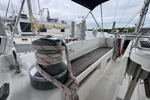 Slide: The Image of 1996 Beneteau 50 sailboat deck with winch and ropes in marina setting. - 49