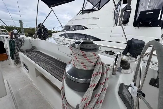 Slide: The Image of 1996 Beneteau 50 sailboat deck with winch and ropes, docked beside another yacht. - 50