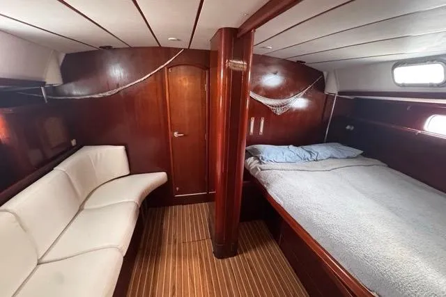 Slide: The Image of Luxurious 1996 Beneteau 50 yacht cabin with wooden interior, bed, and seating area. - 94