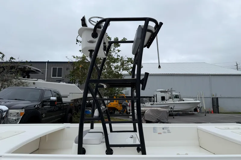 Slide: The Image of 2018 Mako Pro Skiff 19 CC Top Drive boat with elevated helm, parked outdoors. - 6