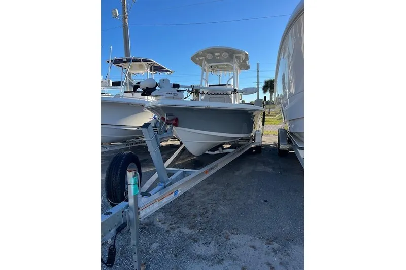 The Image of 2023 Sea Pro 248 Bay boat on trailer, parked outdoors under clear blue sky. - 1