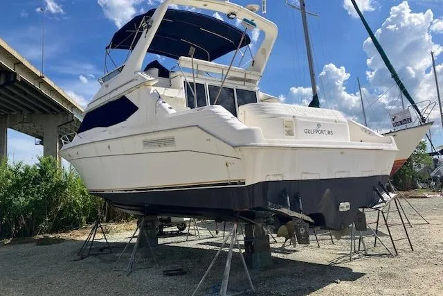 Slide: The Image of 1997 Sea Ray 440 Express yacht on stands, under a clear blue sky. - 4