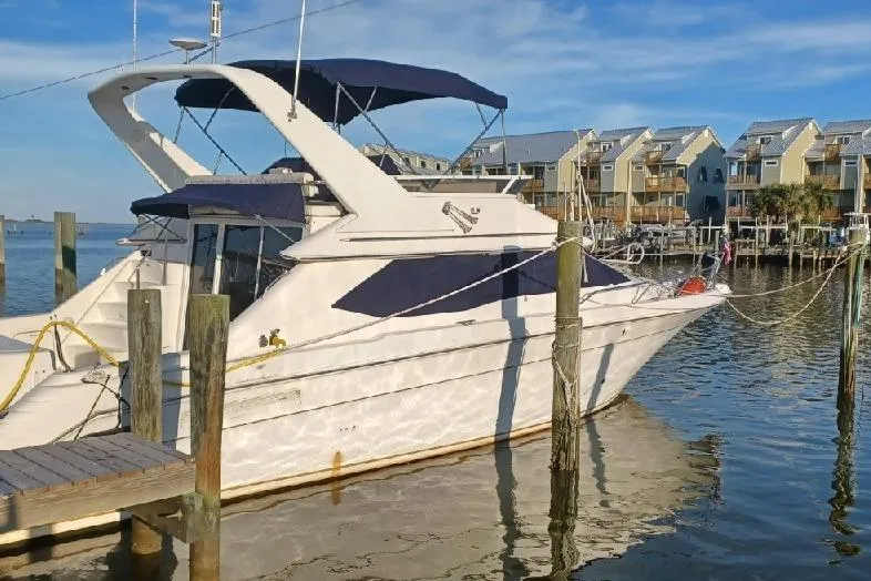 The Image of 1997 Sea Ray 440 Express docked at marina with waterfront homes in background. - 0
