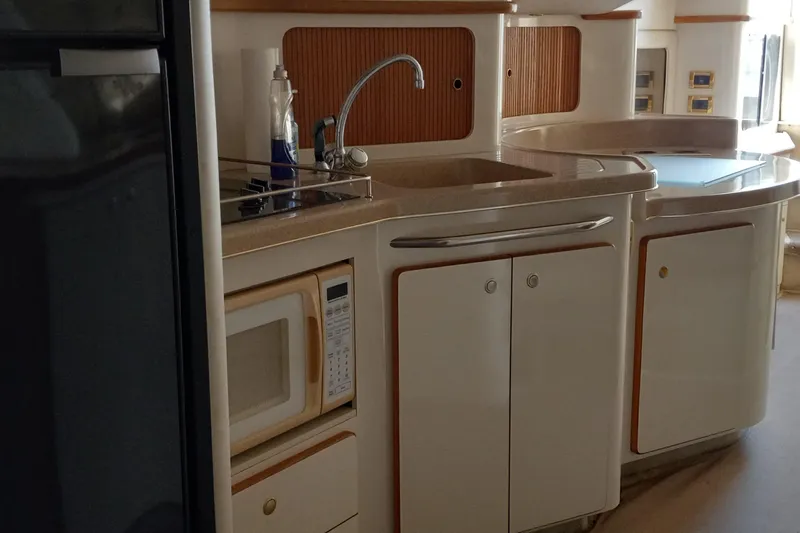 Slide: The Image of 1997 Sea Ray 440 Express yacht kitchen with sink, microwave, and cabinetry. - 13