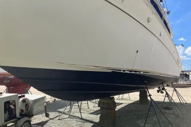 Slide: The Image of 1997 Sea Ray 440 Express yacht on stands, hull view, outdoor setting. - 2