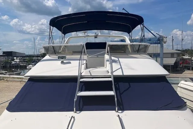 Slide: The Image of 1997 Sea Ray 440 Express yacht with blue canopy, docked under a cloudy sky. - 7