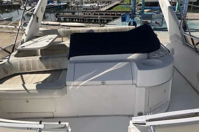 Slide: The Image of 1997 Sea Ray 440 Express yacht interior with seating and table, docked at marina. - 8