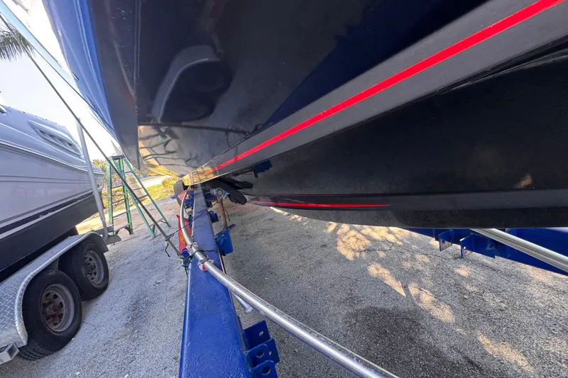 Slide: The Image of 2025 Don Smith Custom 55' boat on trailer, featuring sleek black hull with red stripe. - 27