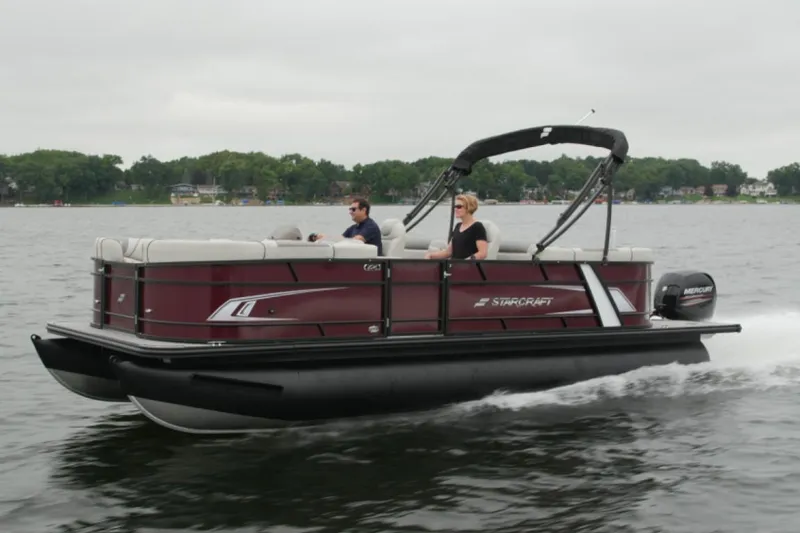 Slide: The Image of 2023 Starcraft EX 22 pontoon boat cruising on a lake. - 2