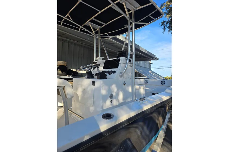 Slide: The Image of 2005 Dusky 203 boat with T-top and console, docked under a metal roof. - 5