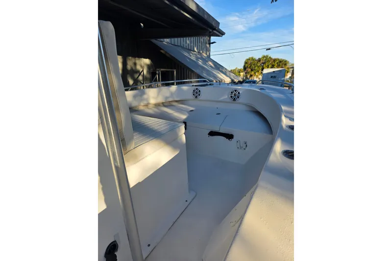 Slide: The Image of 2005 Dusky 203 boat interior with seating and storage, under clear blue sky. - 8