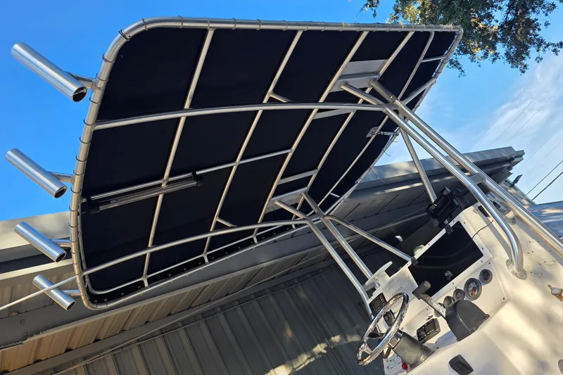 Slide: The Image of T-top and console of a 2005 Dusky 203 boat under a clear sky. - 10