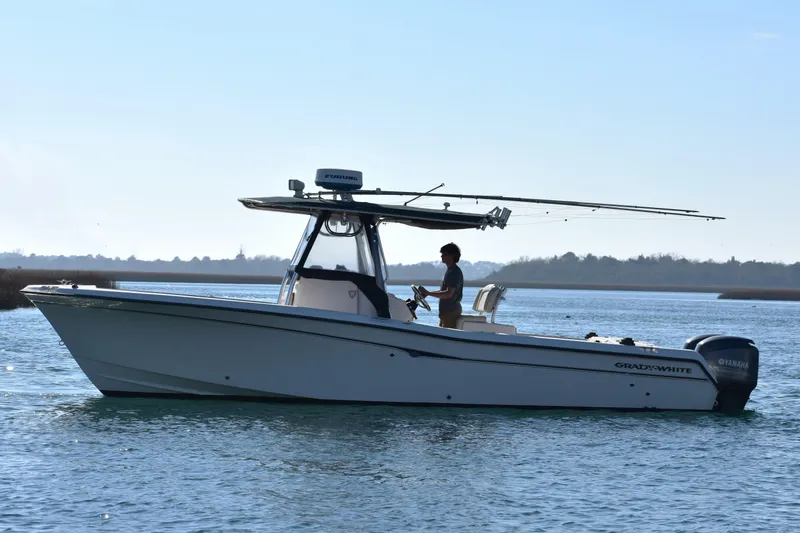 Slide: The Image of 2004 Grady-White Release 283 boat on calm water, side view, with person steering. - 10