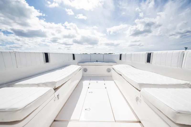 Slide: The Image of 2011 Intrepid 400 Center Console boat interior with white cushioned seating under a cloudy sky. - 20