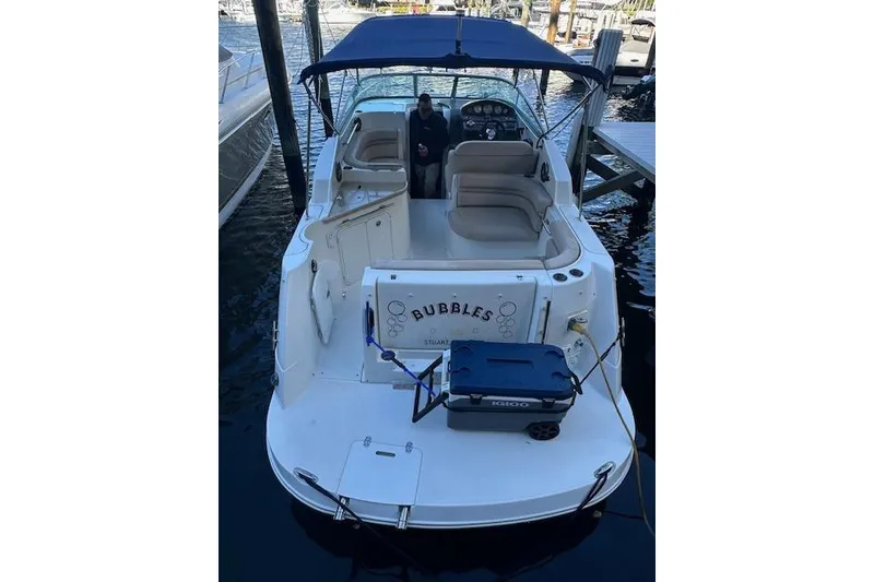 Slide: The Image of 2014 Rinker 260 Express Cruiser docked with blue canopy and seating area. - 2