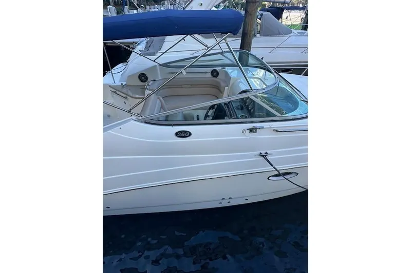 Slide: The Image of 2014 Rinker 260 Express Cruiser docked, featuring sleek white design and blue canopy. - 29