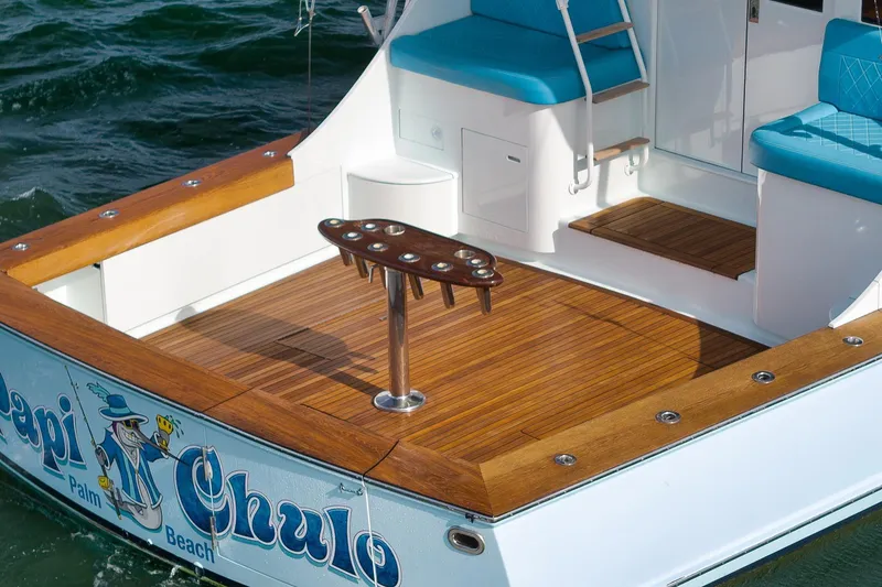Slide: The Image of 1997 Garlington 61 boat deck with teak flooring and blue seating, featuring a fishing rod holder. - 11