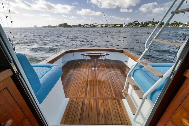 Slide: The Image of 1997 Garlington 61 yacht deck with blue seating, overlooking calm waters and distant shoreline. - 25