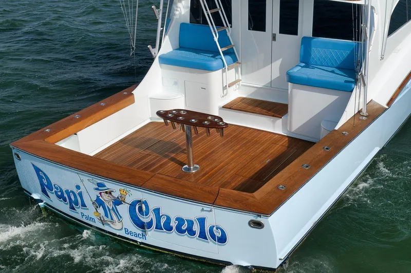 Slide: The Image of 1997 Garlington 61 yacht with wooden deck and blue seating, named "Papi Chulo," in Palm Beach waters. - 9