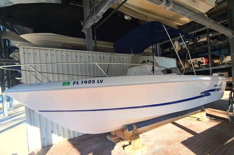 The Image of 2002 Pro-Line 22 Sport boat in storage, featuring a sleek white hull and blue accents. - 0