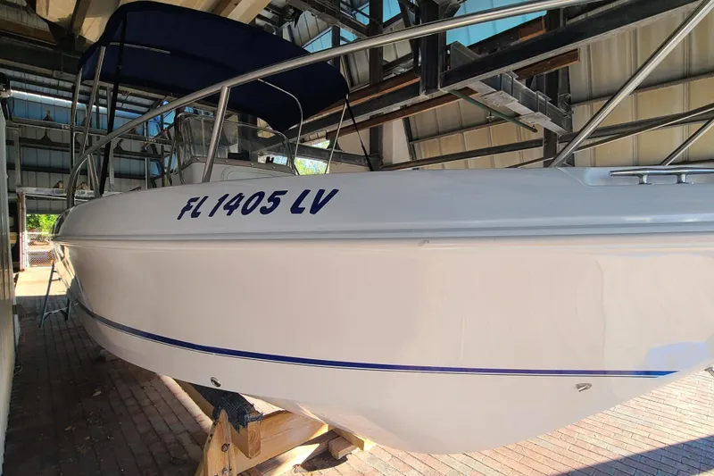 Slide: The Image of 2002 Pro-Line 22 Sport boat in storage, featuring a white hull and blue accents. - 2
